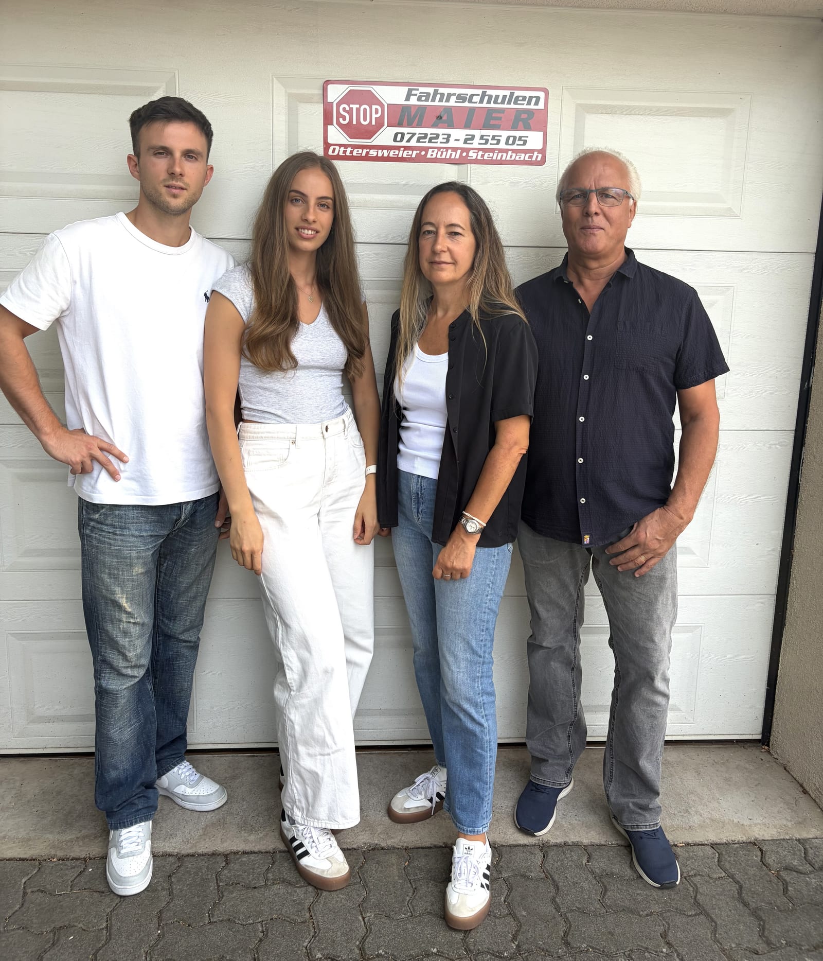 Das Team der Fahrschule Maier vor dem Fahrschulschild